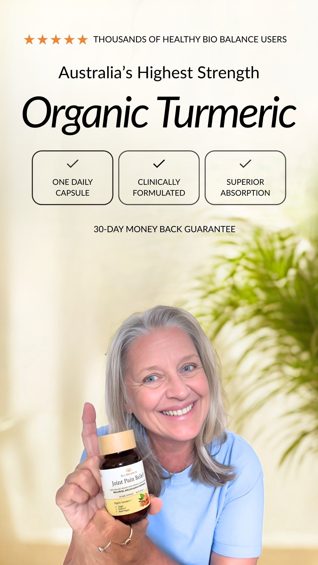 Woman holding a bottle of organic turmeric supplement with a blurred green plant in the background