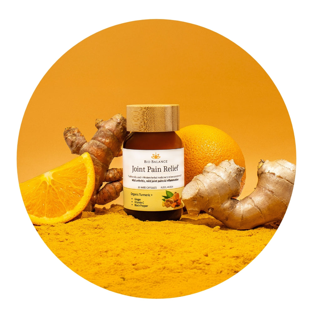 Bottle of Bio Balance Joint Pain Relief with turmeric, ginger, and oranges on a yellow background