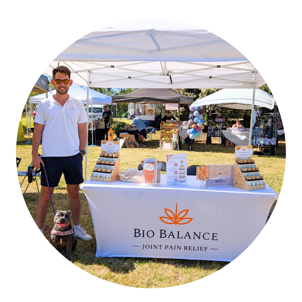 Man standing next to a Bio Balance joint pain relief booth at an outdoor event.